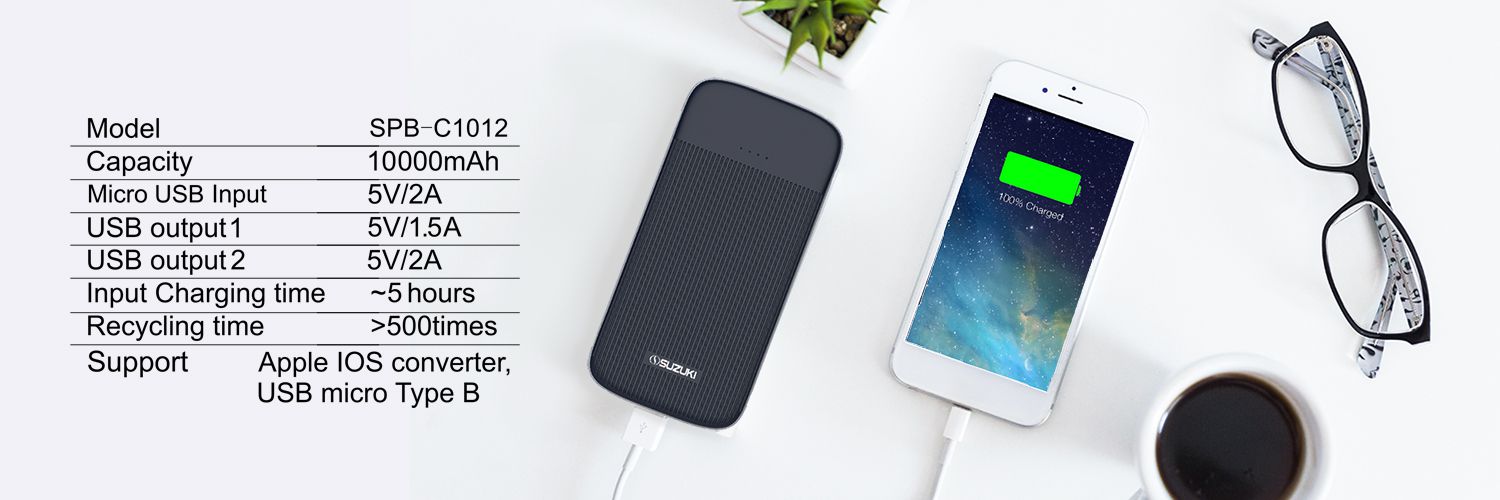 Suzuki SPB-C1012 power bank charging a smartphone next to a technical specification table and eyeglasses on a white desk.