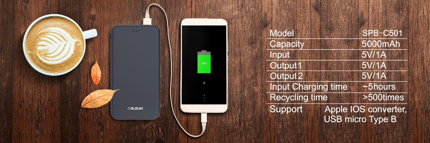 Suzuki power bank charging a white smartphone next to a coffee cup with technical specifications listed on a wooden backgroun