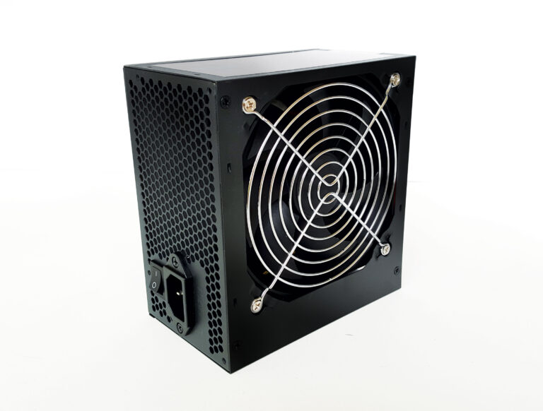 Black computer power supply unit featuring a large cooling fan with a silver wire guard and rear power socket.