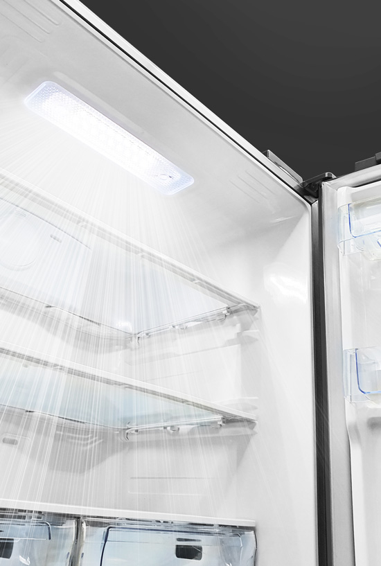 Interior view of a clean, empty white refrigerator featuring bright overhead LED lighting and clear glass shelves.