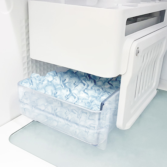 White ice maker unit with a transparent storage drawer pulled out and filled with clear ice cubes.