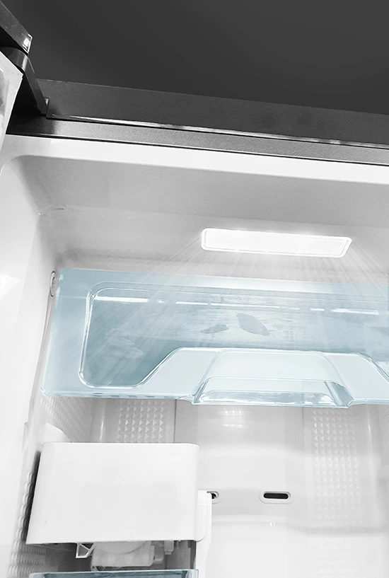 Close-up of a clean white fridge interior featuring a translucent blue drawer cover and bright overhead LED lighting.