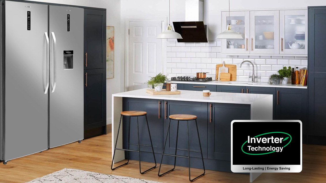 Stainless steel side-by-side refrigerator in a modern kitchen featuring blue cabinets and an Inverter Technology badge.