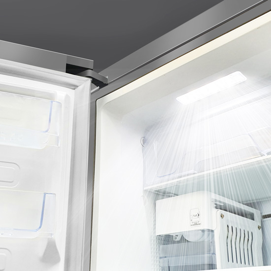 Interior view of an open refrigerator showing cold air circulation streams flowing from the top lighting unit.