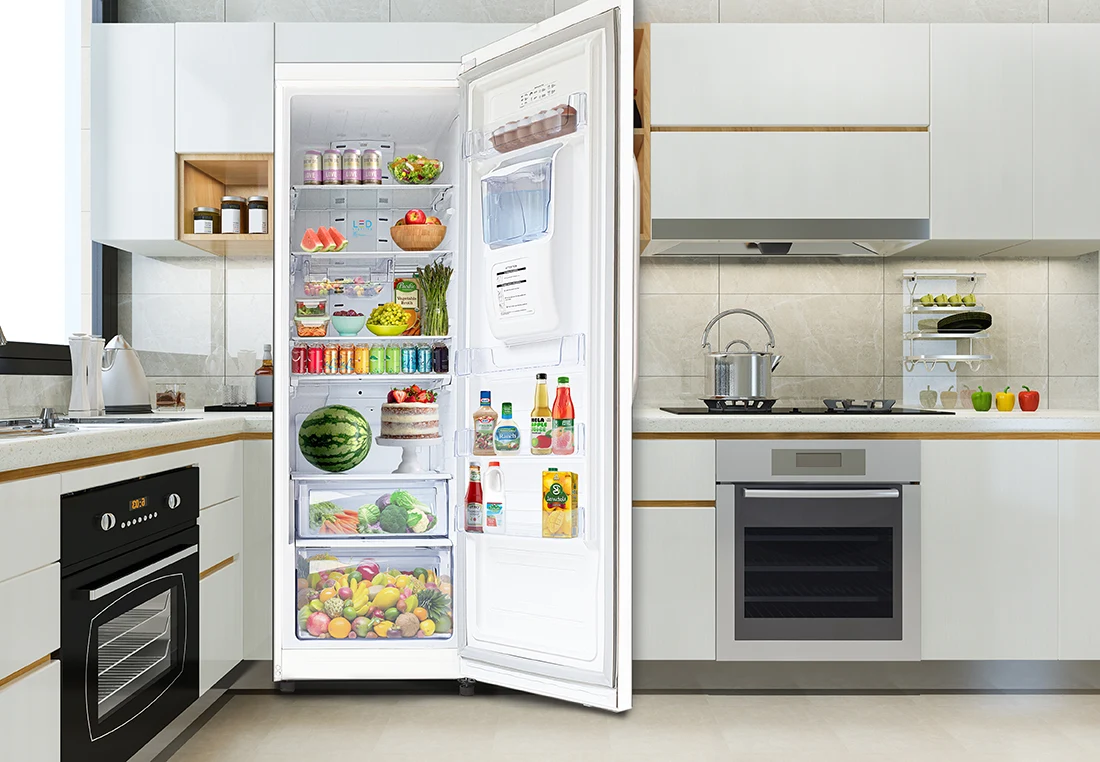 An open white refrigerator fully stocked with fresh fruits, vegetables, drinks, and condiments in a bright modern kitchen.