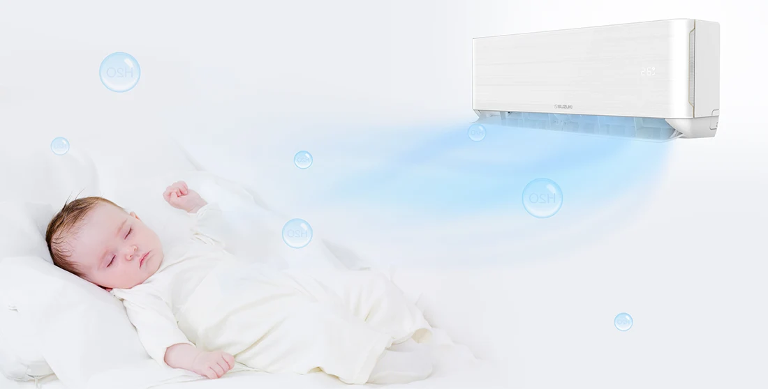 Sleeping baby in white clothes receiving a gentle cool breeze from a wall-mounted air conditioner