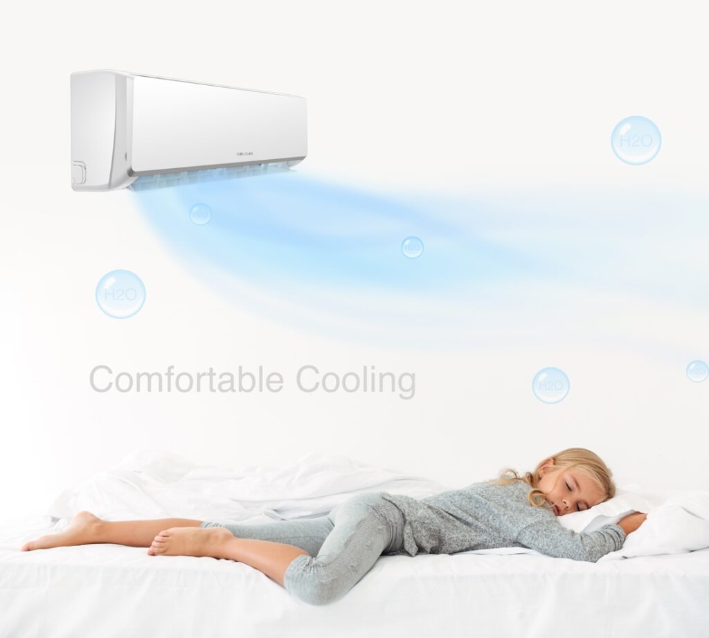 A child sleeping peacefully on a white bed under a cool breeze from a wall-mounted air conditioner