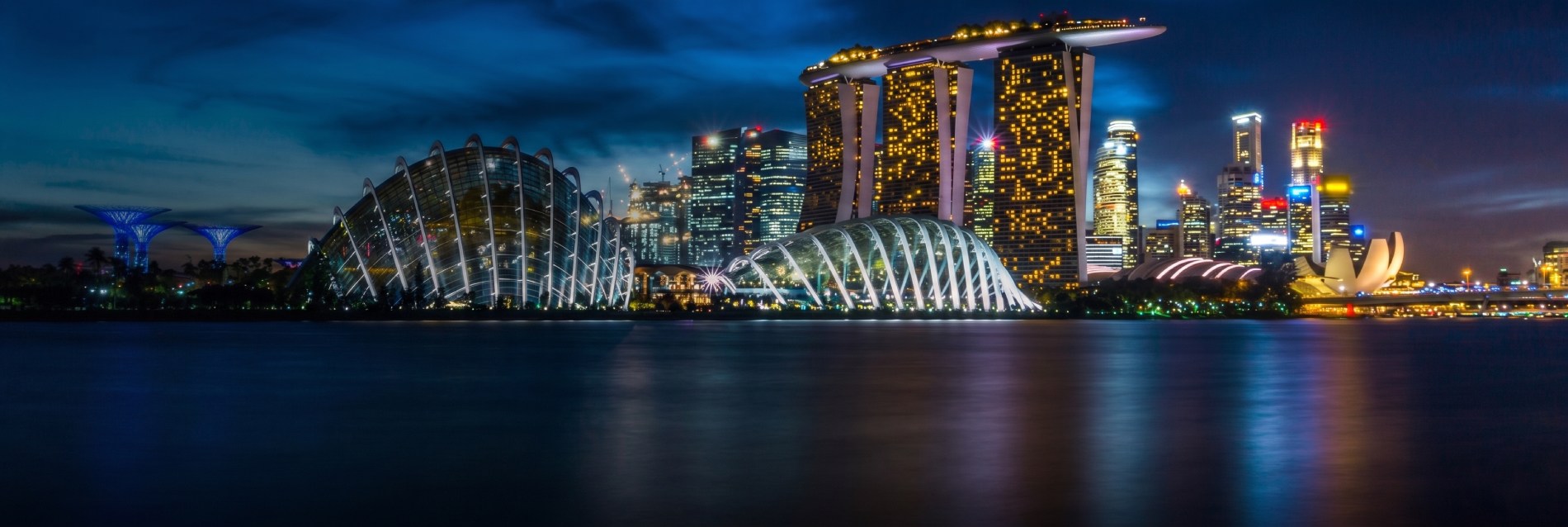 Illuminated Marina Bay Sands hotel and Gardens by the Bay domes reflecting on the water at night