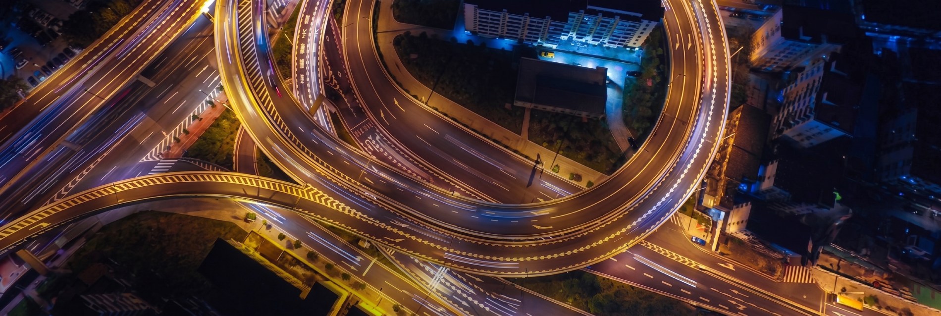 Aerial view of a complex multi-level highway interchange with long exposure light trails from traffic